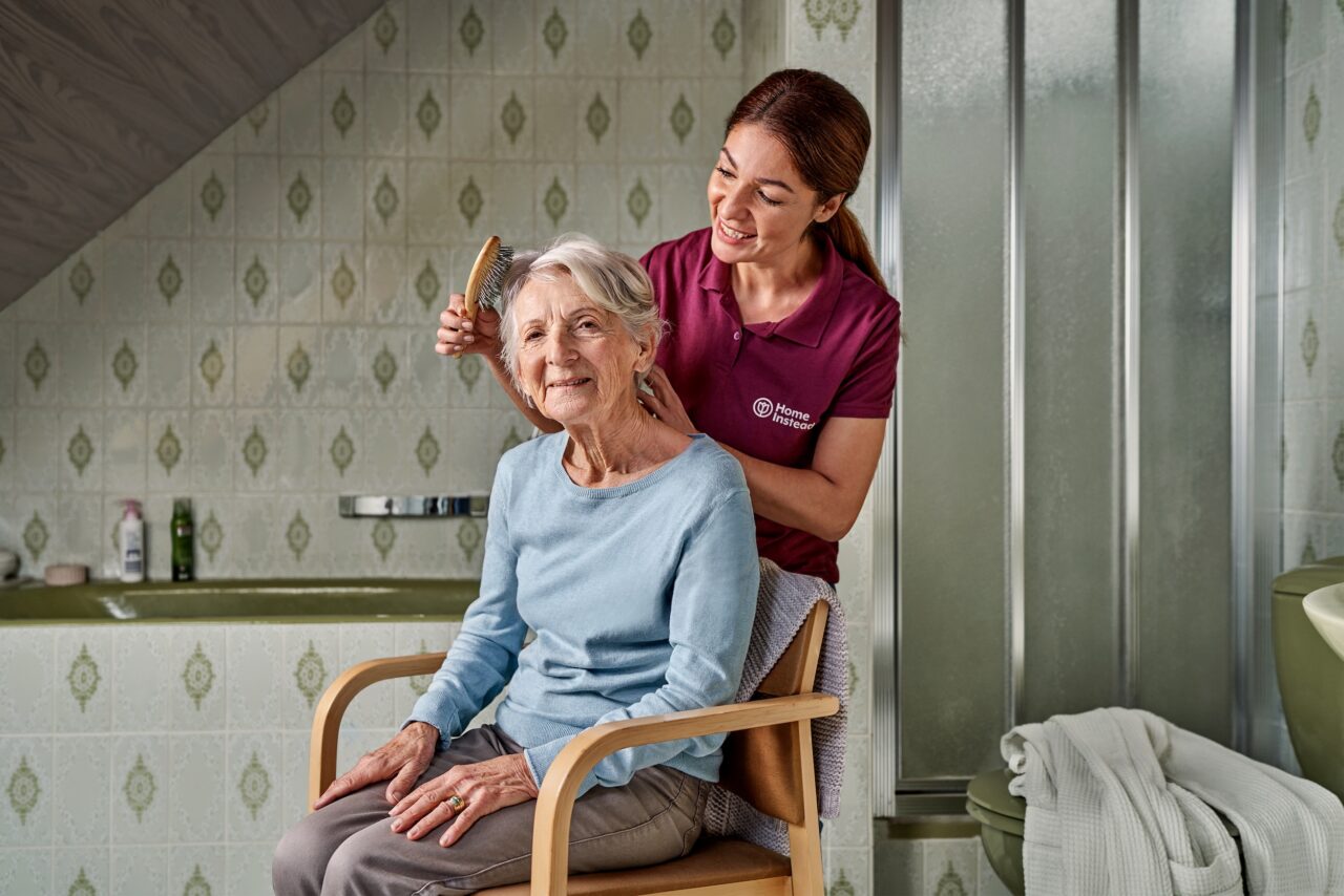 Betreuungskraft kaemmt Seniorin