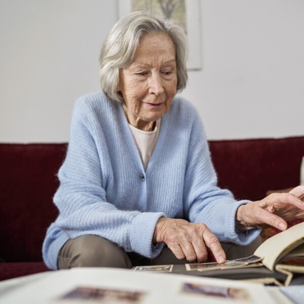 Seniorin blättert vor Einsamkeit in Fotoalbum
