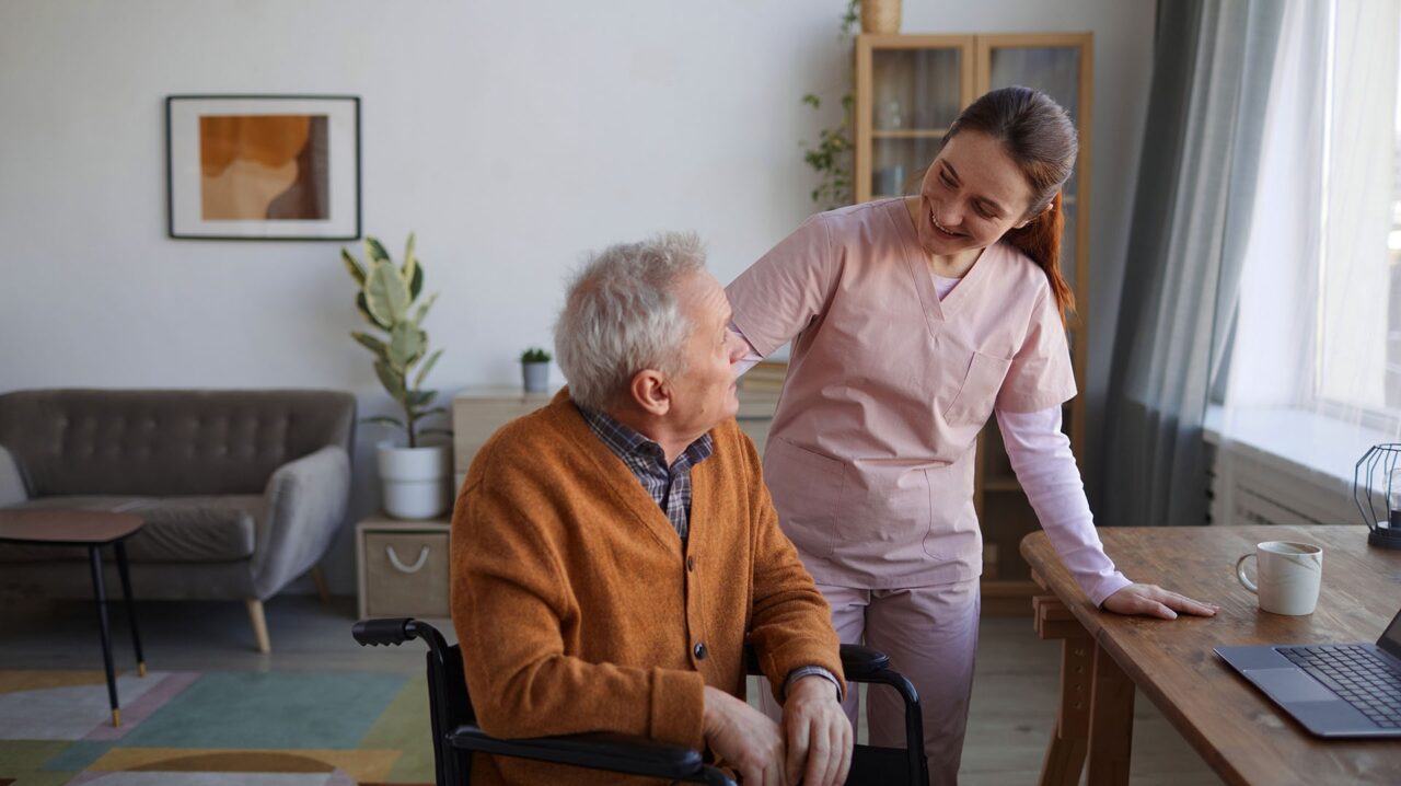 Pflegekraft spricht mit älterem Mann