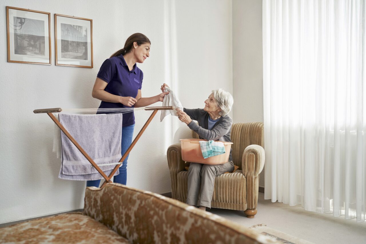 Betreuungskraft macht Wäsche von Seniorin